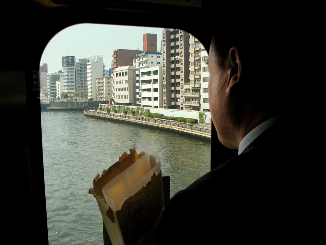 a salaryman looking a the Sumida river from the Sobu line train