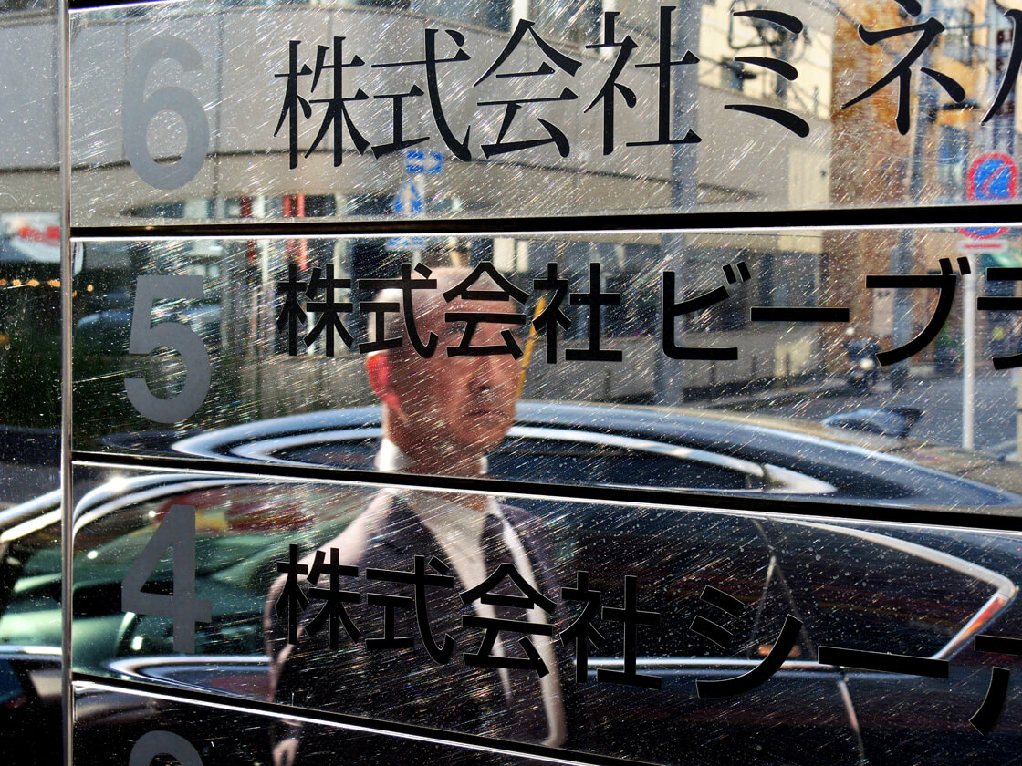 the reflection of a salaryman in a building in Kanda